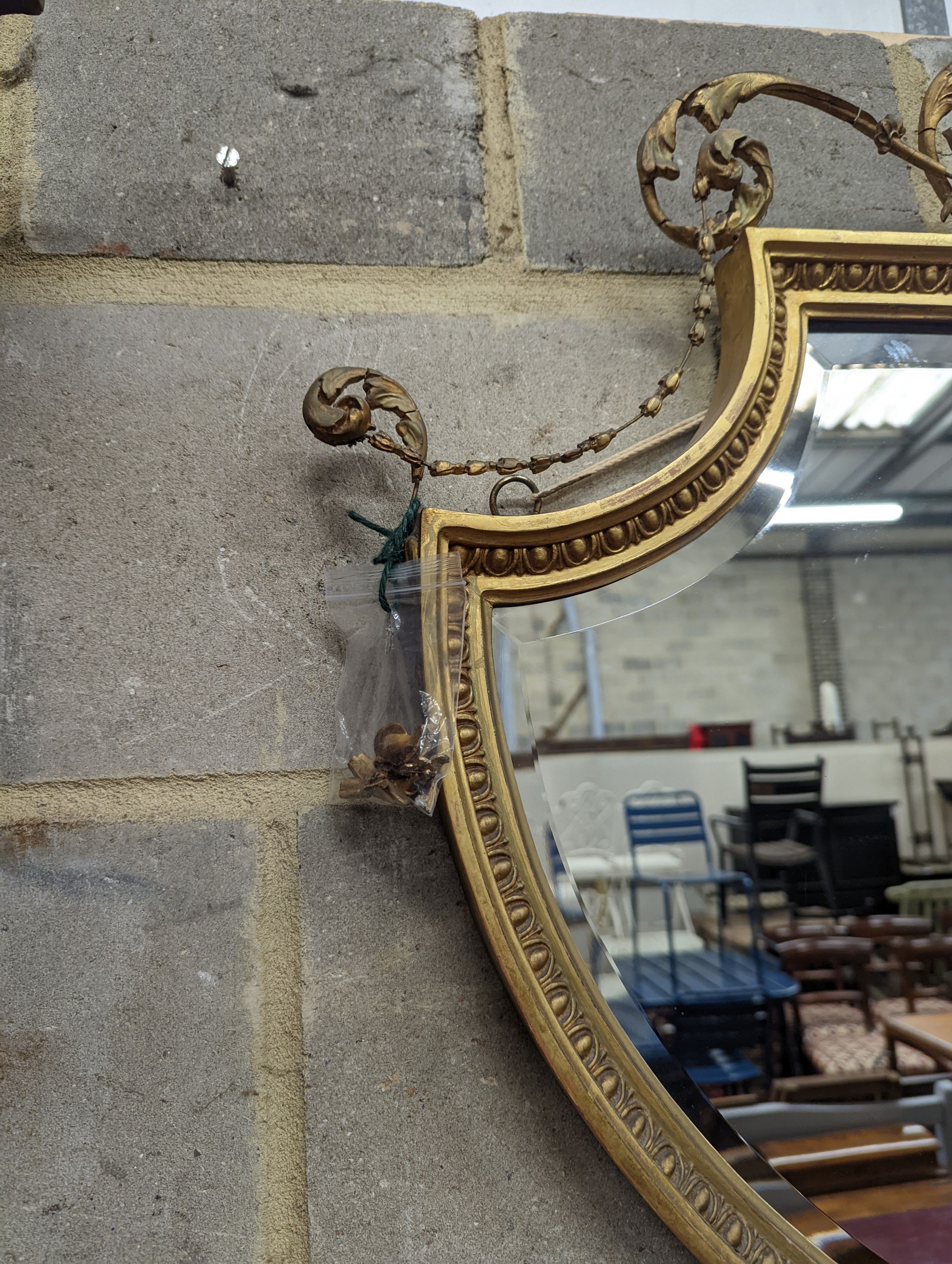 An Edwardian Adam design giltwood and gesso shield shaped wall mirror, width 92cm, height 94cm